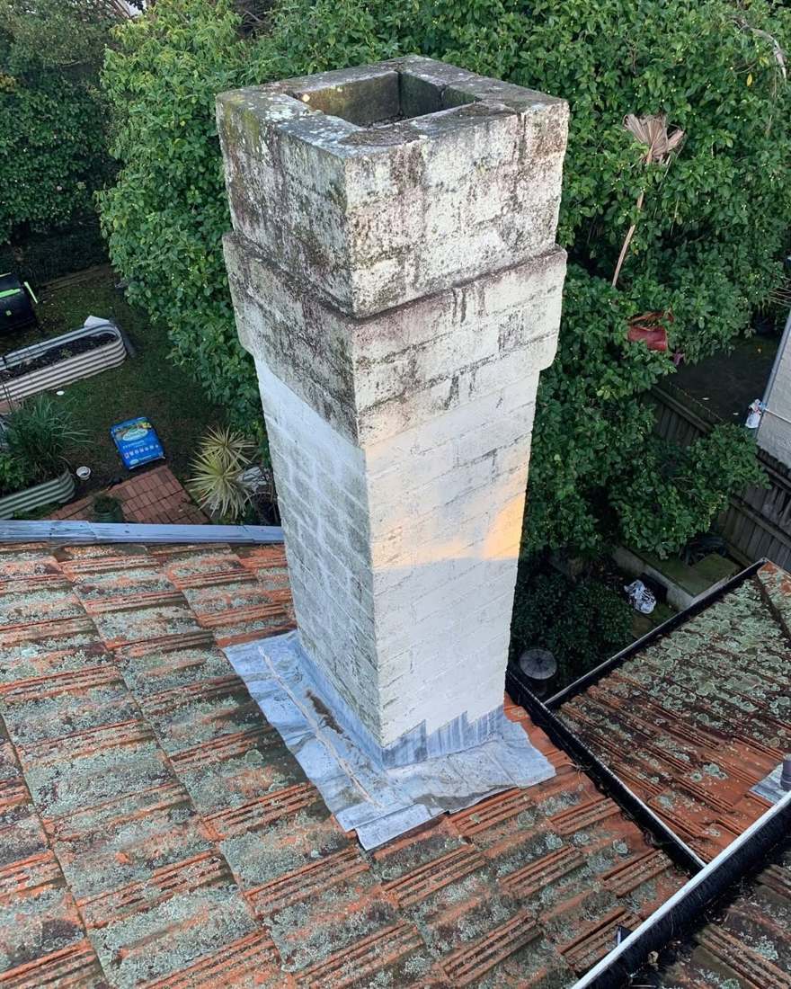 Chimney on a tiled roof with new flashing at its base