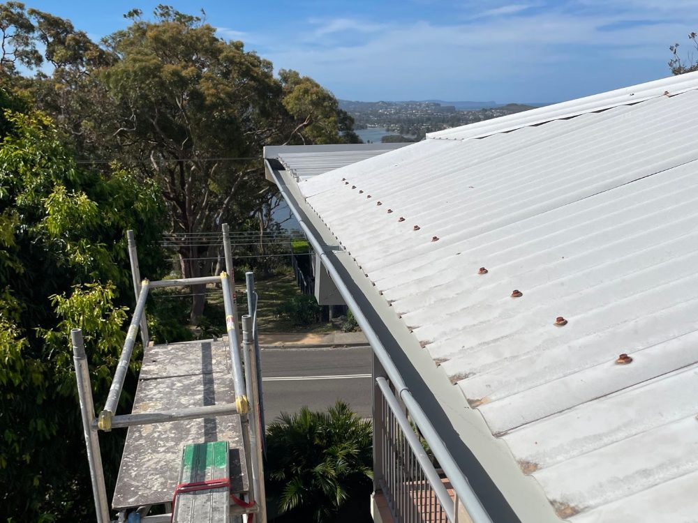 New gutters going on from scaffold two storeys up, with the ocean behind