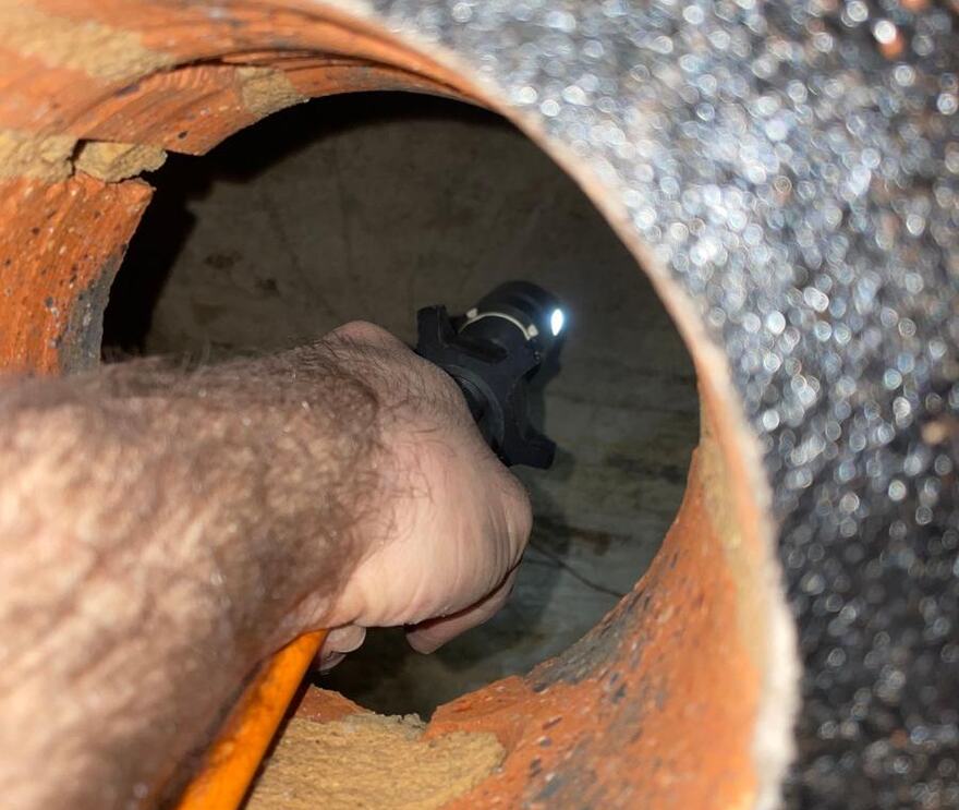Torch held inside a large old earthenware sewer pipe showing the inside wall