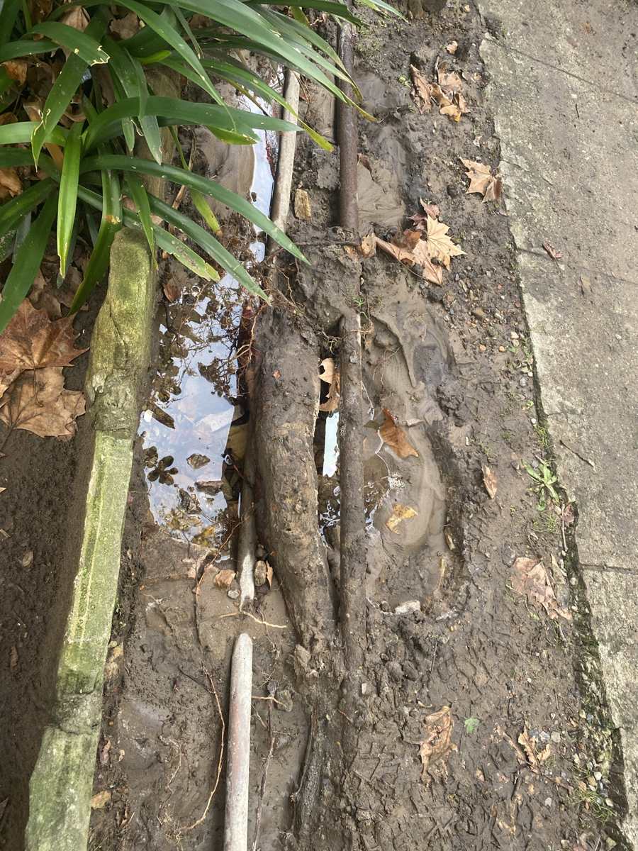 Old corroded pipework uncovered in a trench beside a house