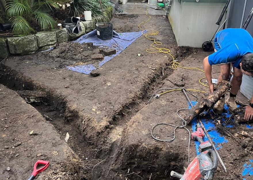 Open trench in a backyard with the old clay sewer line exposed